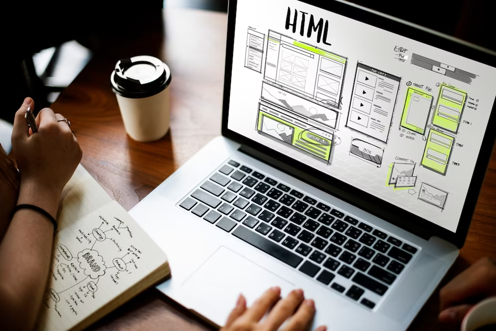 Laptop screen displaying wireframes and HTML structure of a website